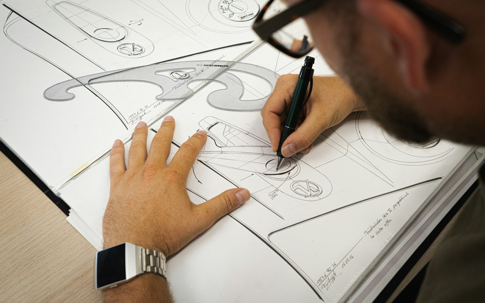 Designer drawing a product sketch with a pen at a desk