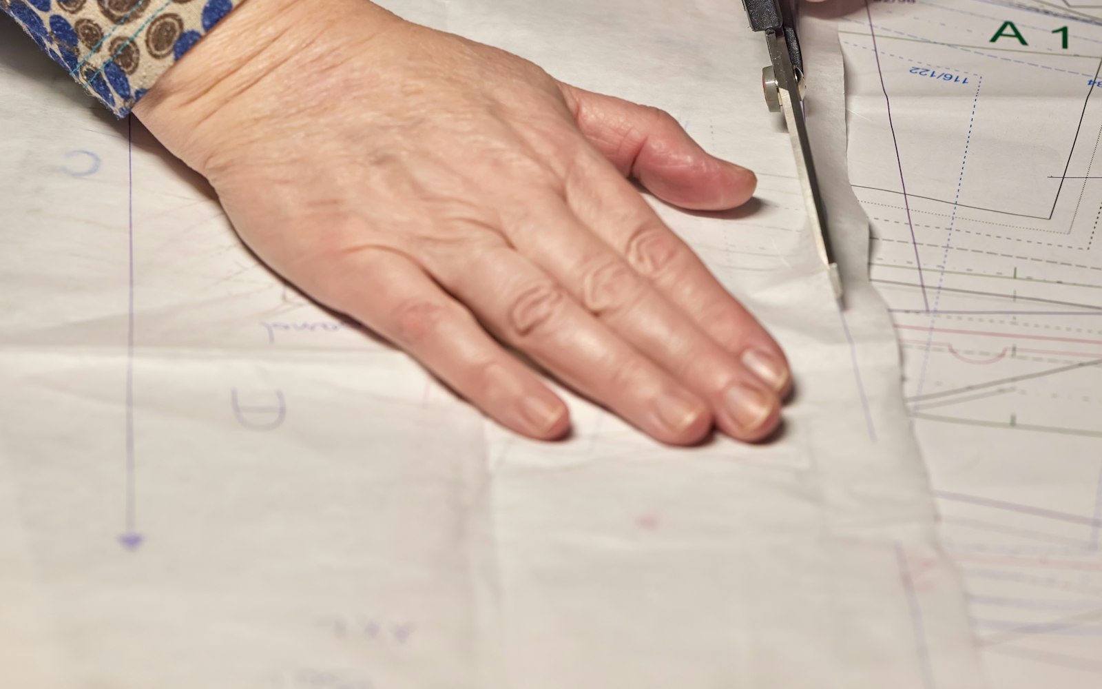 Hands cutting a paper sewing pattern with scissors