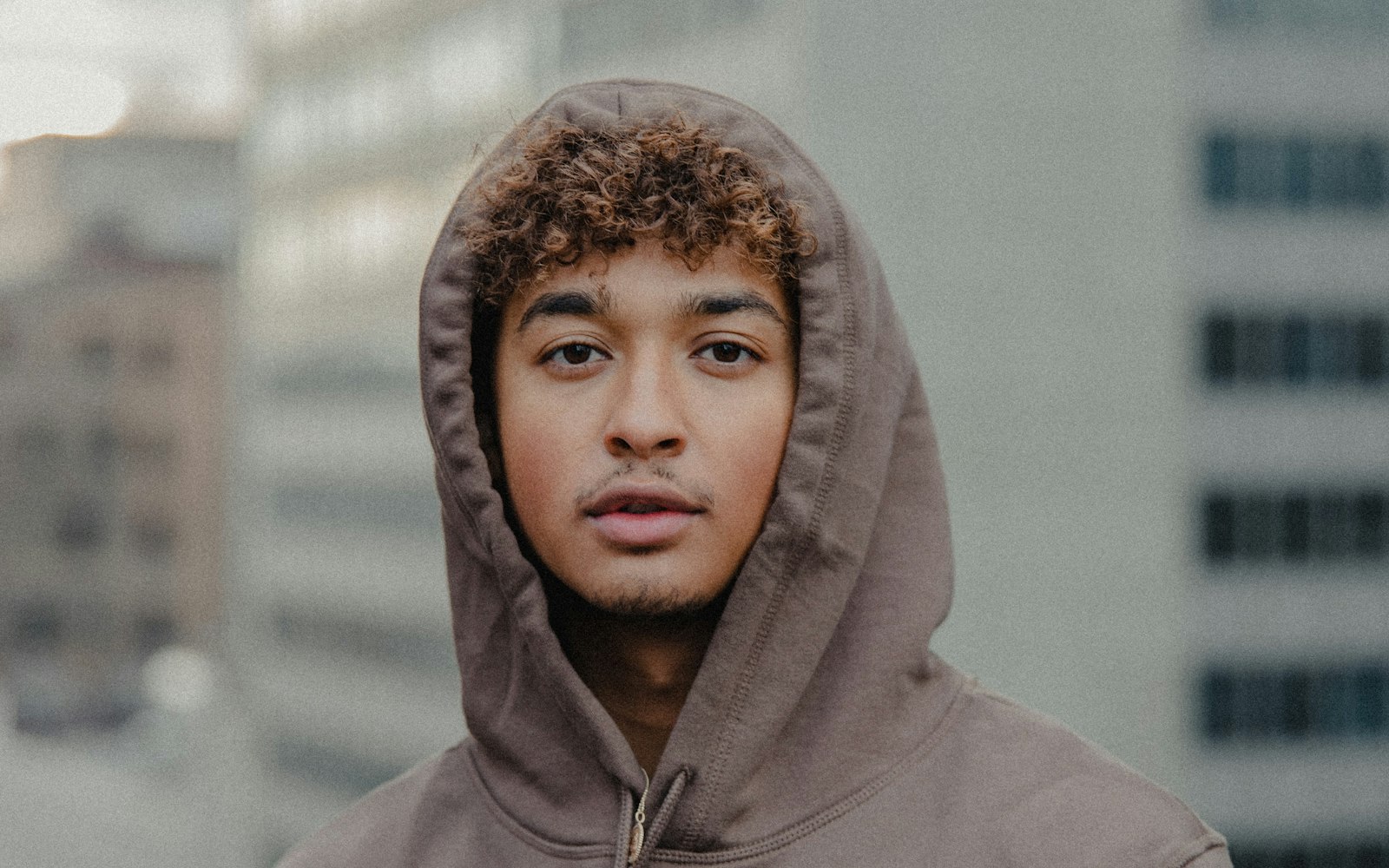Man wearing a brown hoodie with the hood up outdoors