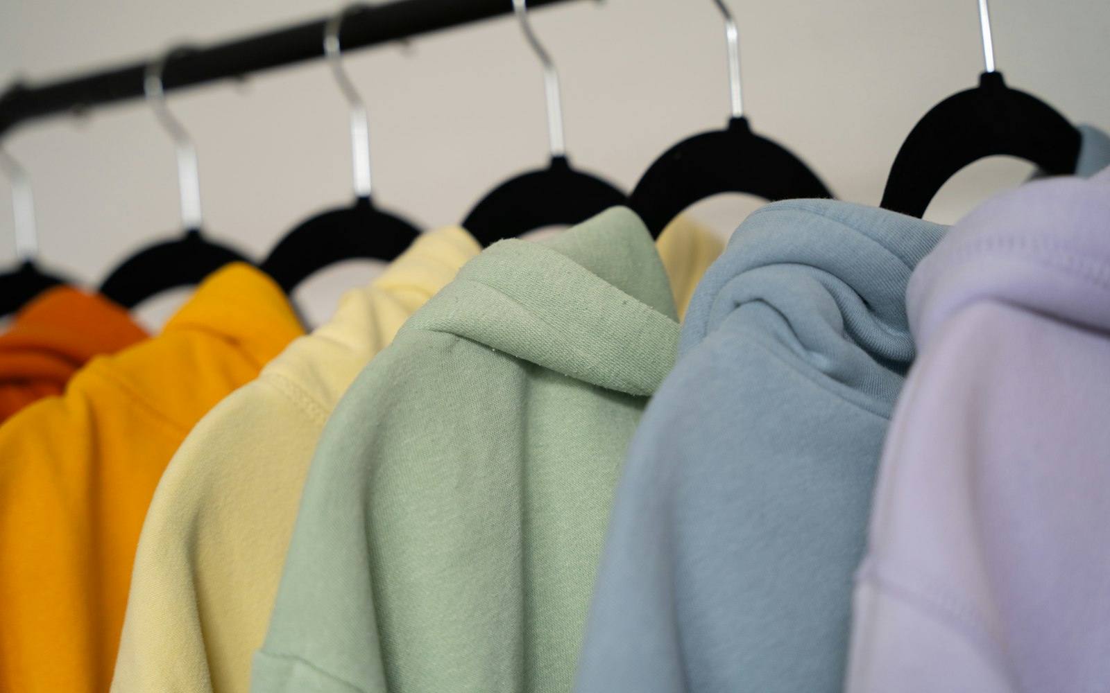 Row of pastel hoodies hanging on a clothing rail